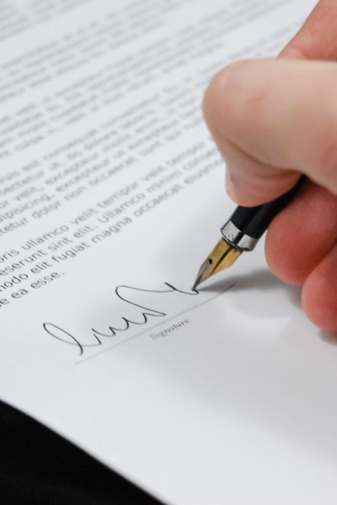 Close-up of a hand signing a legal document with a fountain pen, symbolizing signature and agreement.