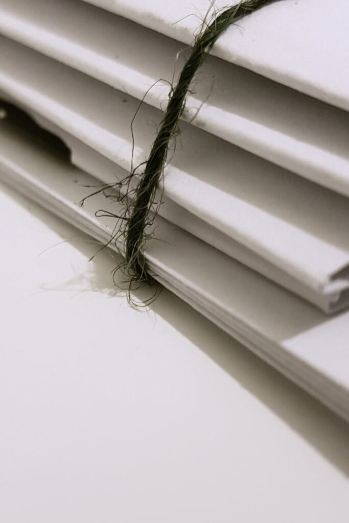 Pile of white envelopes tied with a green string, showcasing a minimalist design.