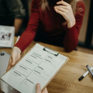 Woman sitting at a desk holding a clipboard and reviewing a resume during a job interview.